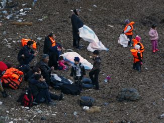 Migrants wearing life jackets wait for a dinghy to sail off for the Greek island of Lesbos from the Turkish coastal town of Dikili