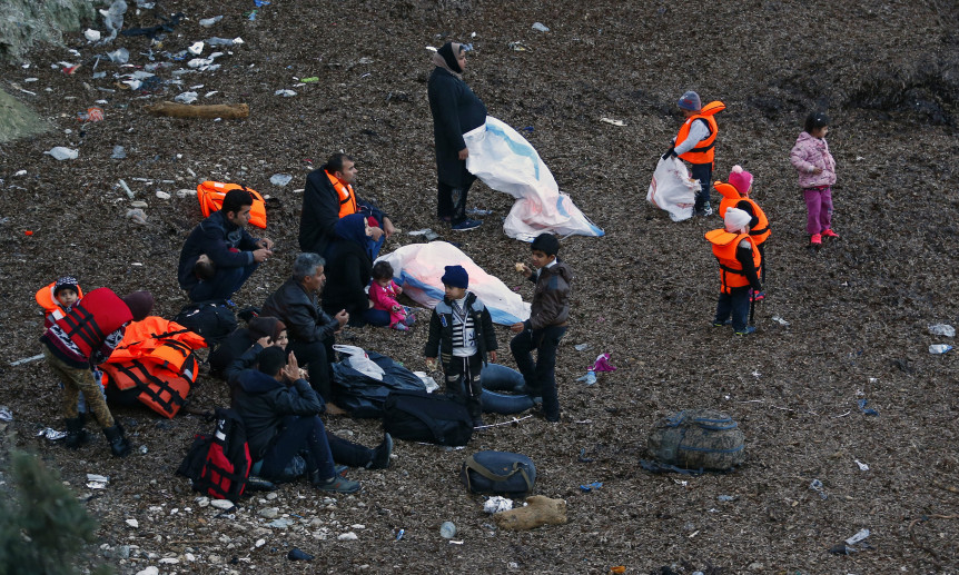 Migrants wearing life jackets wait for a dinghy to sail off for the Greek island of Lesbos from the Turkish coastal town of Dikili