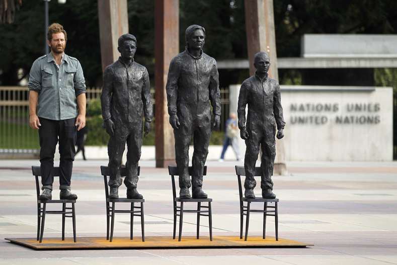 Italian artist Davide Dormino stands on an empty chair in his installation "Anything to Say?"