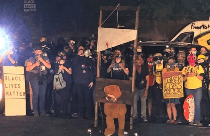 Far-left Portland rioters wheel out the guillotine and burn American flags