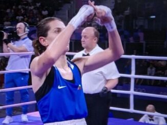 Female boxer defeated by another biological male holds up X sign in defiance.